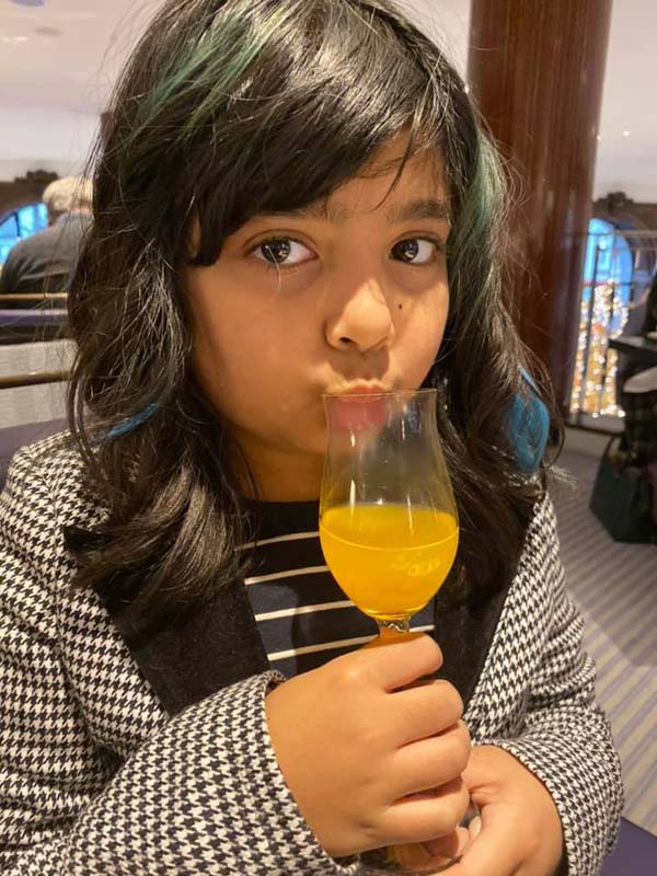 A young girl sips on orange juice at Charlie and the Chocolate Factory Afternoon Tea at One Aldwych.