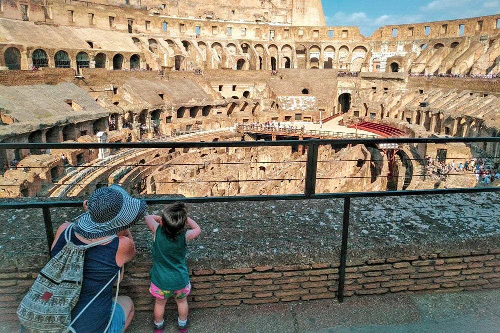 A mom and her young daughter look into the center of the Colosseum, one of the best places to visit on an Italy itinerary with kids. 