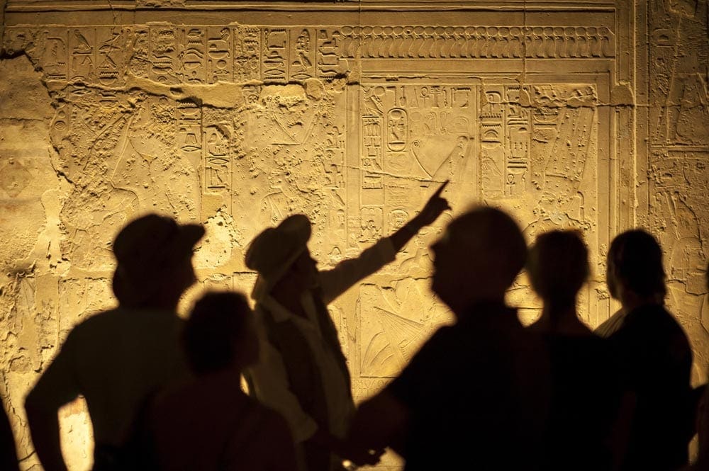 People shadows on Egyptian hieroglyphs in a pyramid. 