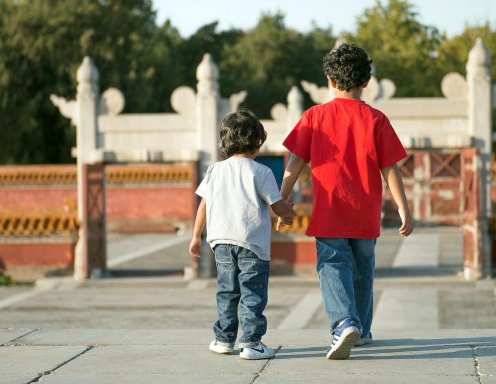 Two boys hold hands while walking in China.
