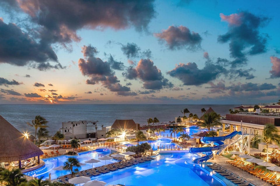 Beautiful view of multiple pools at night of The Grand Moon Palace Cancun, one of the best all-inclusive resorts in the Caribbean for families.