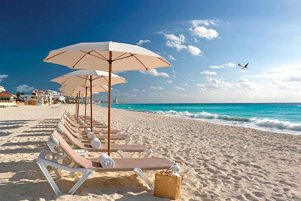 Beautiful sandy beach with lounge chairs and beach umbrellas at The Grand Moon Palace.