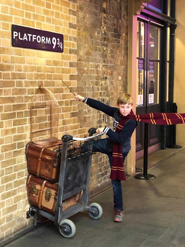 A young boy pretends to enter platform 9 3/4 in London.