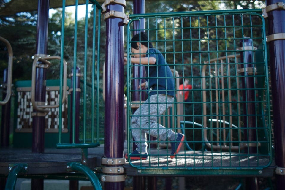 A young child walks through a playground bridge at Koret Playground.