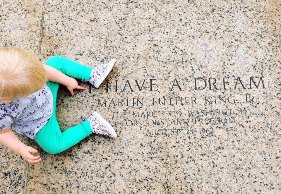 A small boy sits above the text "I Have a Dream" etched in marble.