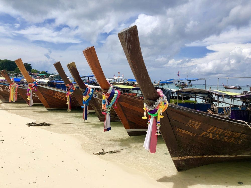 A line of traditional wooden boats on the beach of one of the Phi Phi Islands in Thailand.
