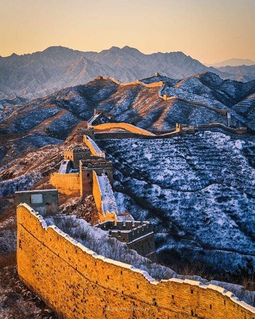 A long view of the Great Wall of China during a sunset.