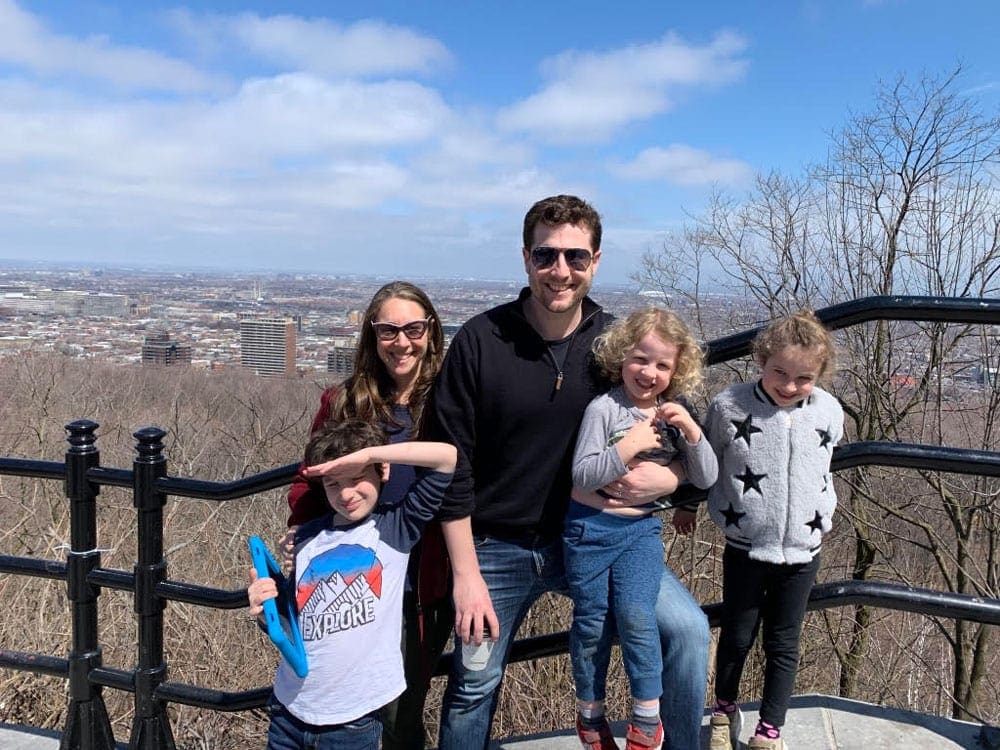 A family of fives stands with a view of Montreal behind them.