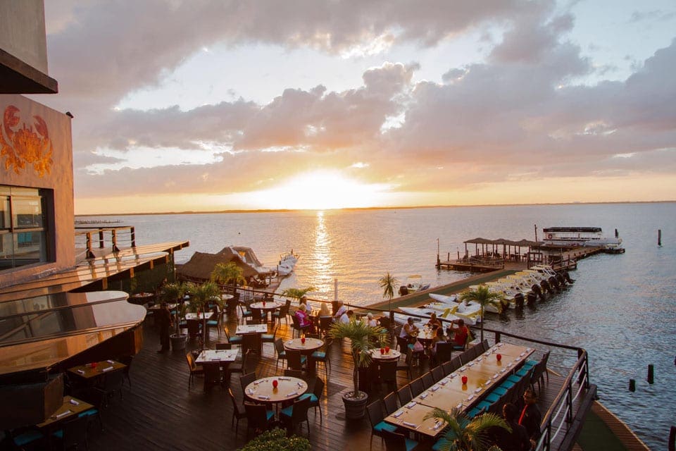An aerial view of the outdoor patio of The Crab House, featuring a stunning view of the water at sunset.
