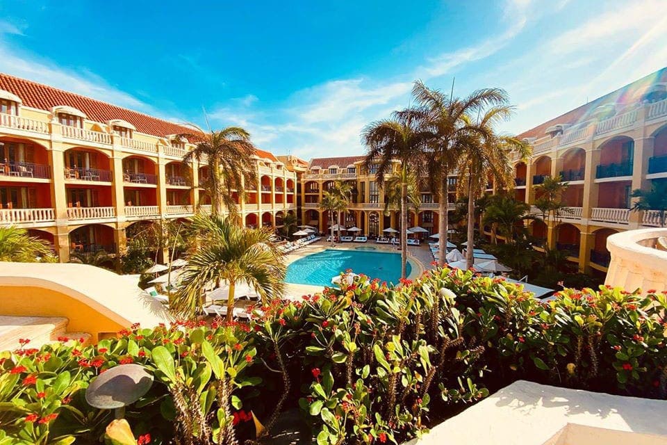 An aerial view of the courtyard with Sofitel Legend Santa Clara Cartagena, featuring a pool an lush palms.