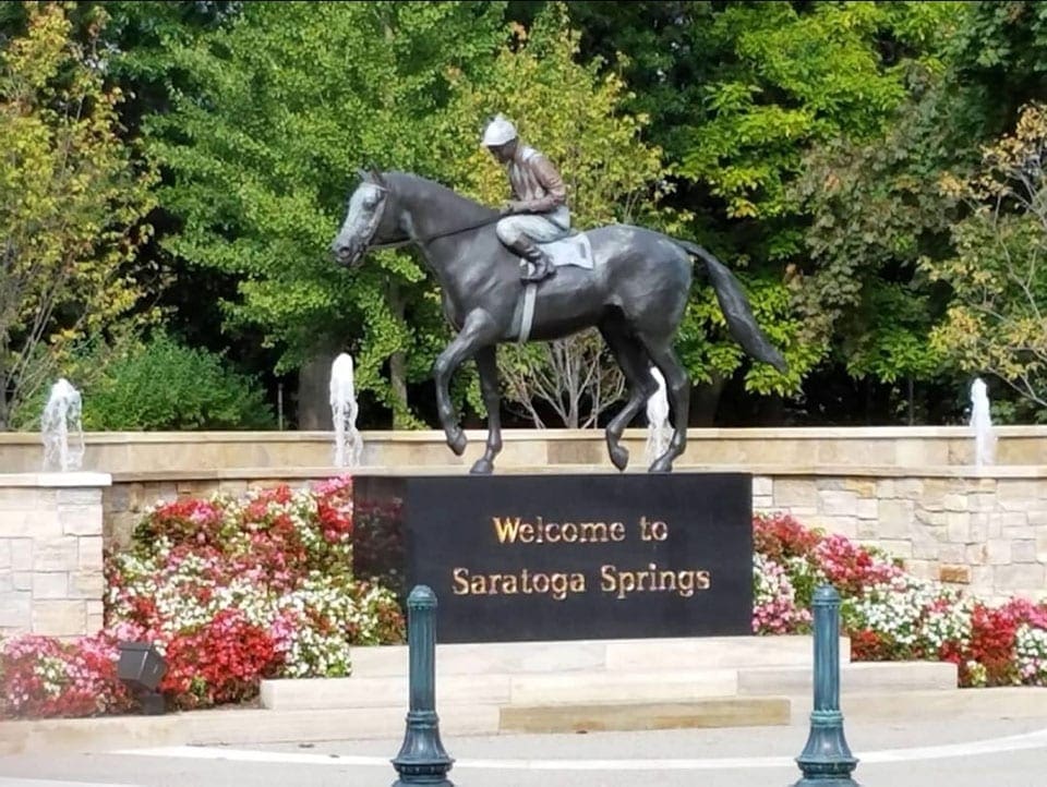 The "Welcome to Saratoga Springs" sign, atop of which sits a horse and rider statue in Saratoga Springs, one of the Best Cute Towns To Visit With Kids Near NYC.