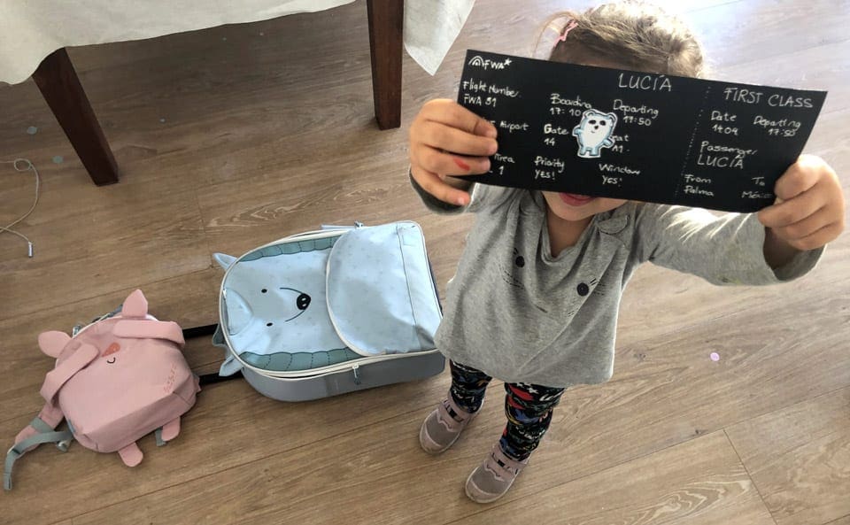 Little girl holding a homemade boarding pass for her virtual vacation to Mexico.