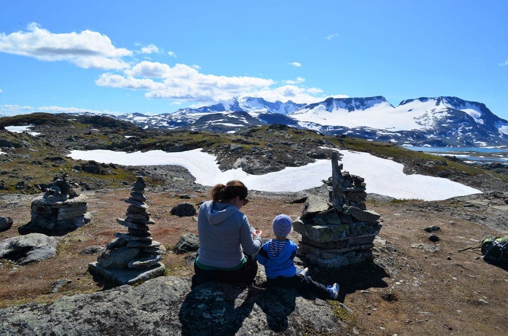 Mother and child sit viewing snow covered mountains in Norway.
