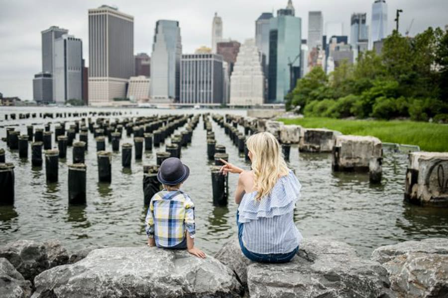 Mom and son sitting in NYC pier facing water and Jersey City.