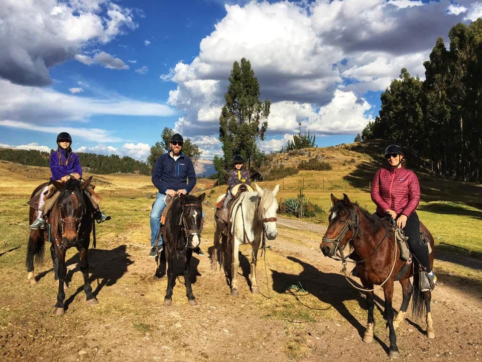 A family of four, all on horseback, poses while trekking along the Inca Trail in Peru.