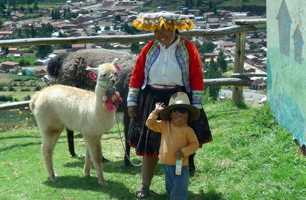 Peruvian mother and child stands with their two llamas.