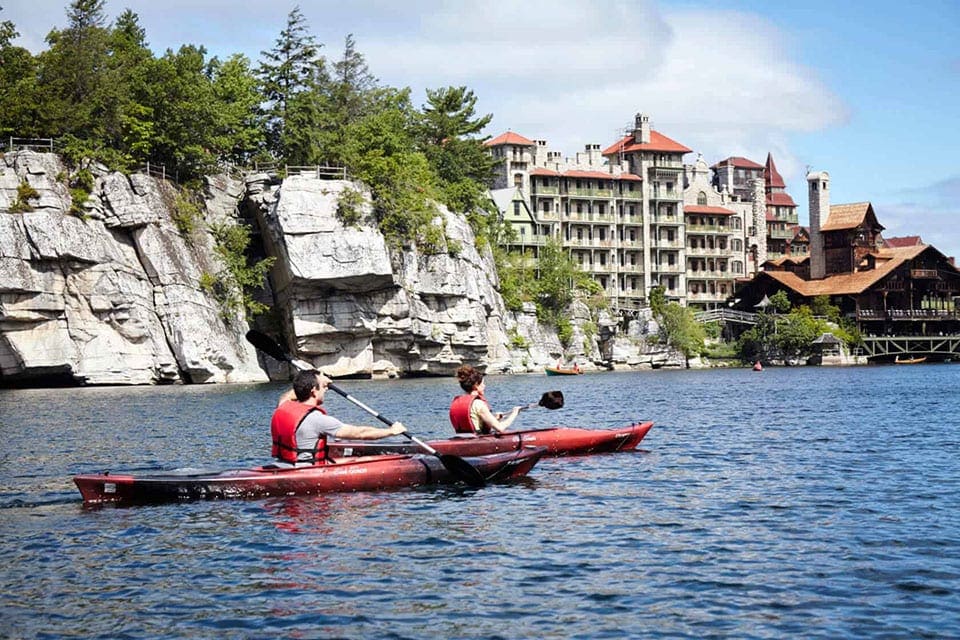 Man and woman kayaking on Mohonk Lake at the Mohonk Mountain House, one of the best all-inclusive hotels in the United States for families.