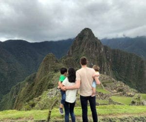 Family of four admiring the view at top of the mountain in Macchu Picchu, Peru
