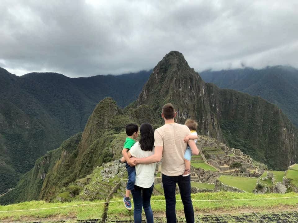 Family of four admiring the view at top of the mountain in Macchu Picchu, Peru.