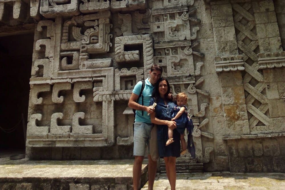 Family of three standing in front of a pre-historic temple in Mexico.
