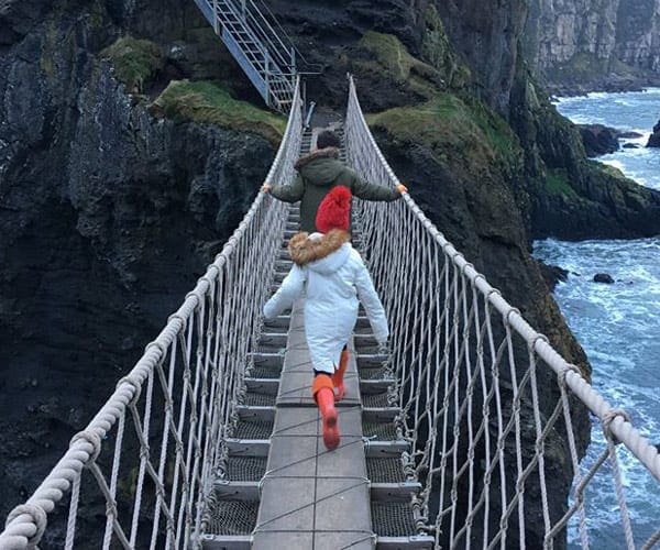 Two kids walking on the rope bridge in Ireland