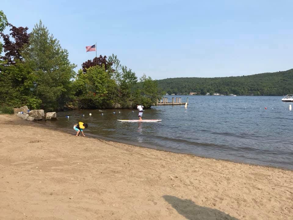 Kids playing on a beach with paddleboard on Lake George