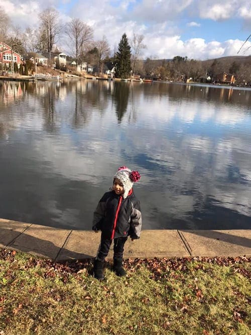 A toddler boy stands in front of Greenwood Lake, one of the best lakes near New York City for families.