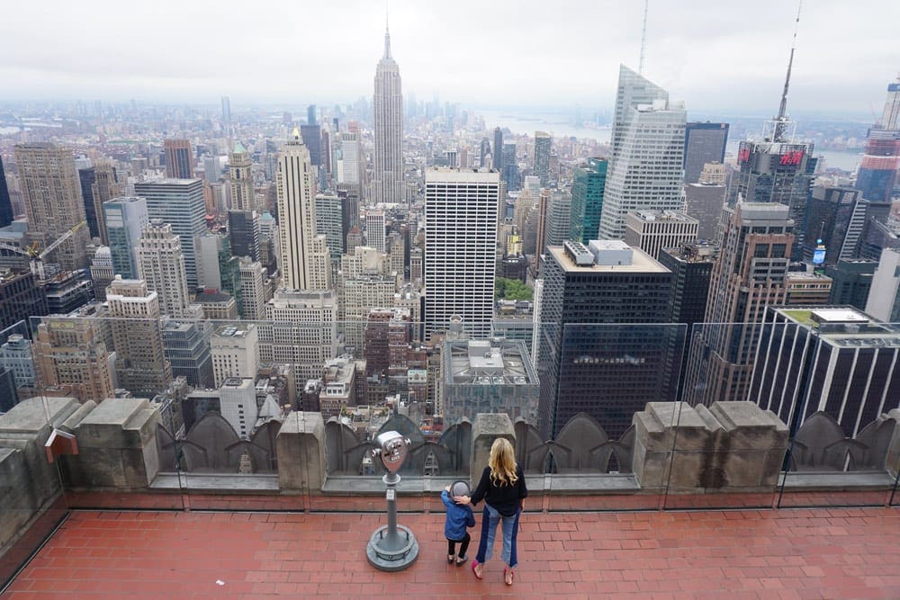Mom and son looking at the NYC skyline from a the roof at Top of the Rock in NYC.