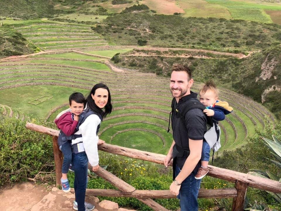 Family of four standing in front of a Peruvian landmark part of Machu Picchu.