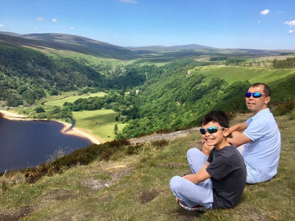 Dan and son sitting along a scenic overlook in Ireland, one of the top places in travel in 2023 with kids.