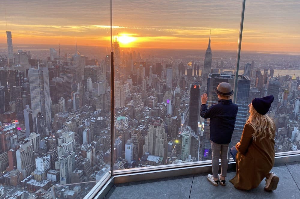 Mom and son watching the sunset from empire state building with Manhattan skyline in New York City.