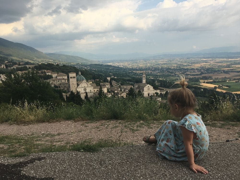 Child looking over the city of Assisi, Italy, one of the best day trips and things to do Rome with toddlers.