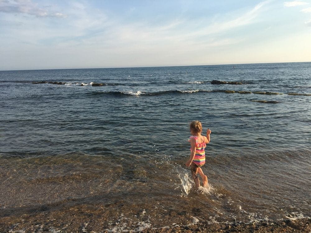 Child in walking into the water at a public beach in Santa Marinella, Italy