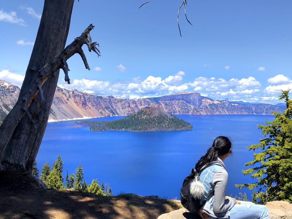 Girl sit looking out onto Crater Lake.