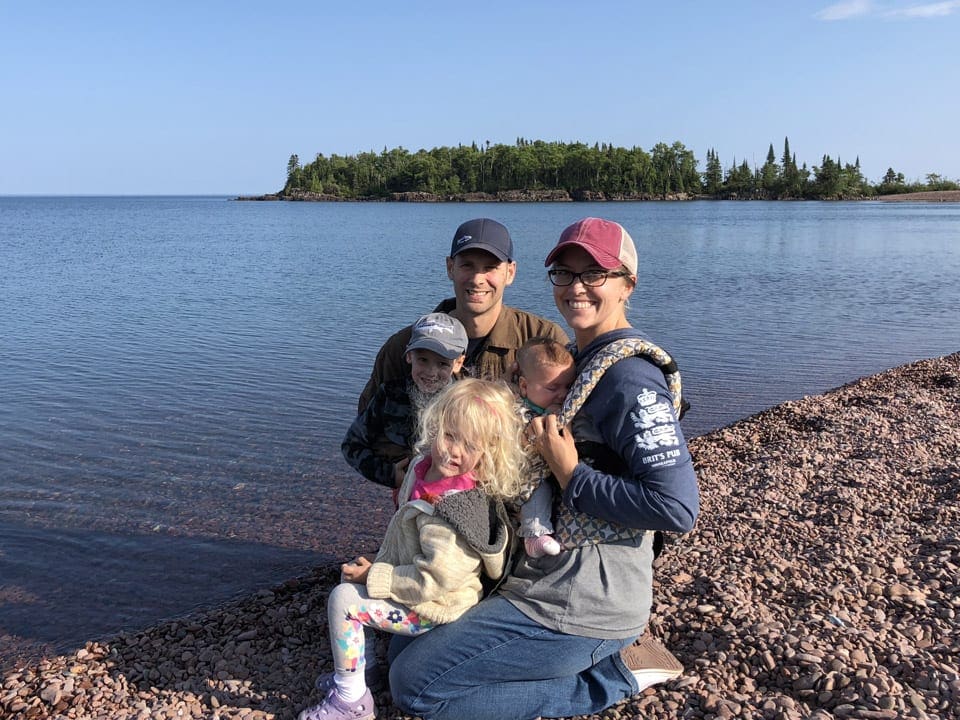 Family with a baby and two toddler posing on a pebble beach at Lake Superior