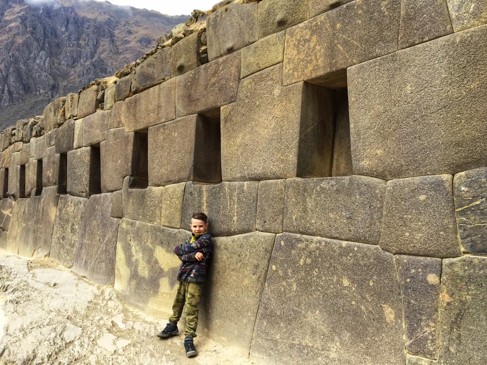 Boy stands along a wall of a ruin in Ollantaytambo, Peru, the third stop on our virtual vacation from home to Peru.