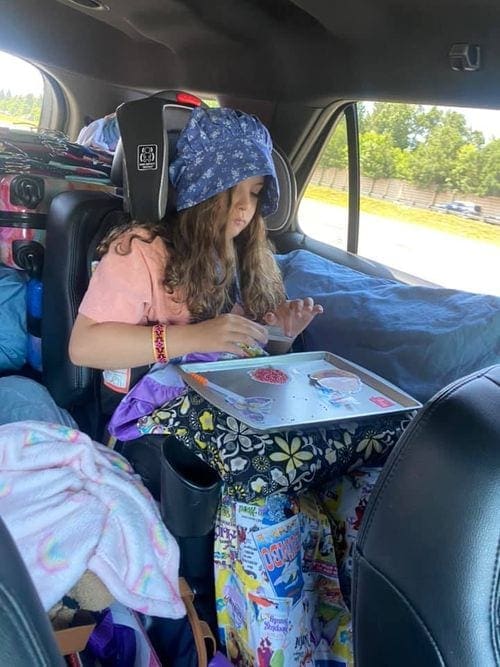 Girl plays within a car on a road trip.