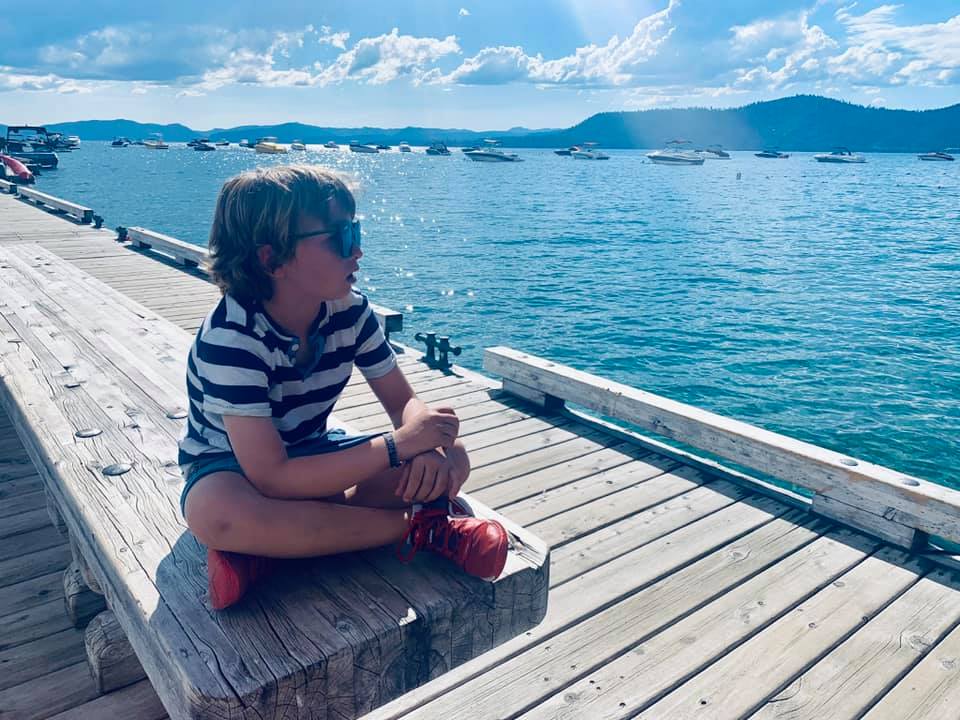 Boy sits alone on a dock on Lake Tahoe.