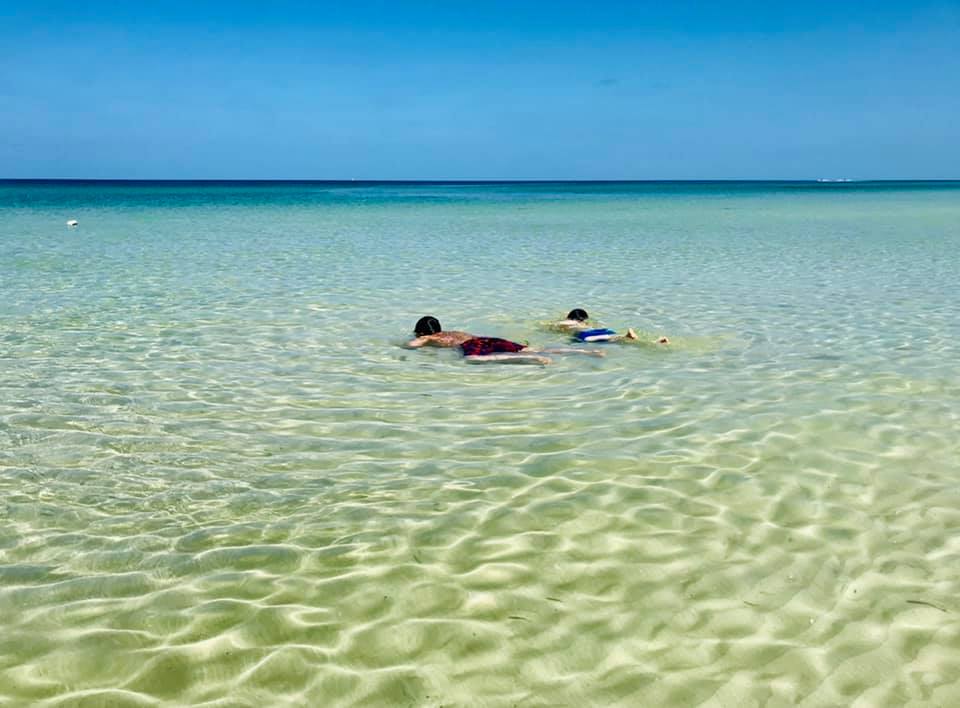 Two children laying face down in clear ocean water in Naples Marco Island, one of the best Florida beaches for families.