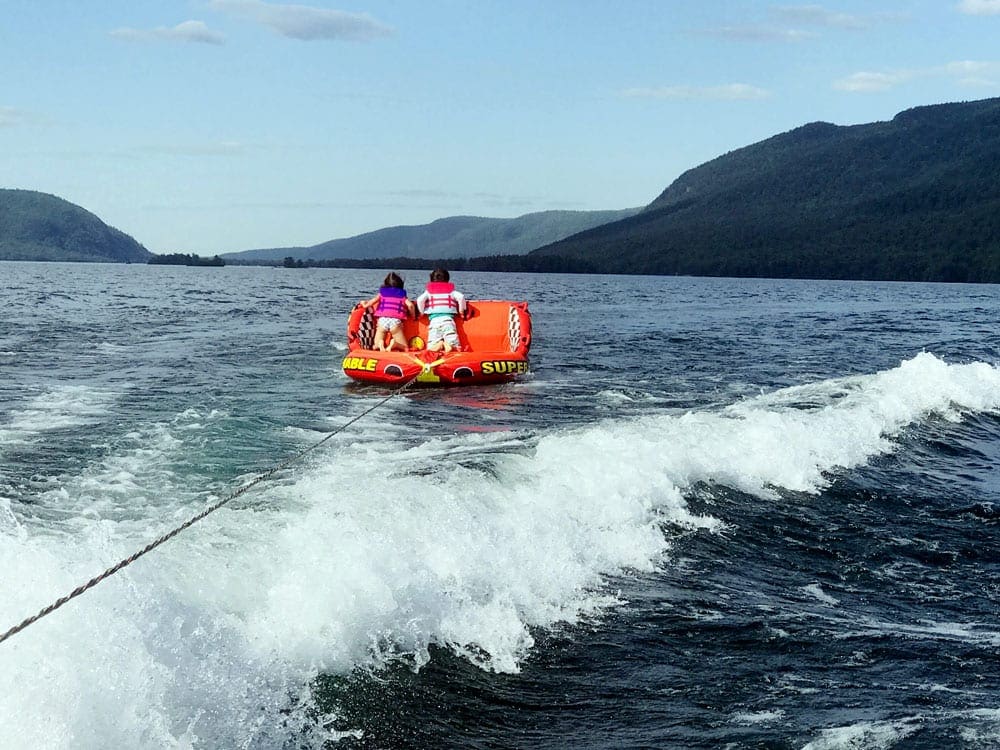 Boy and a girl in a orange towable tubing on Lake George