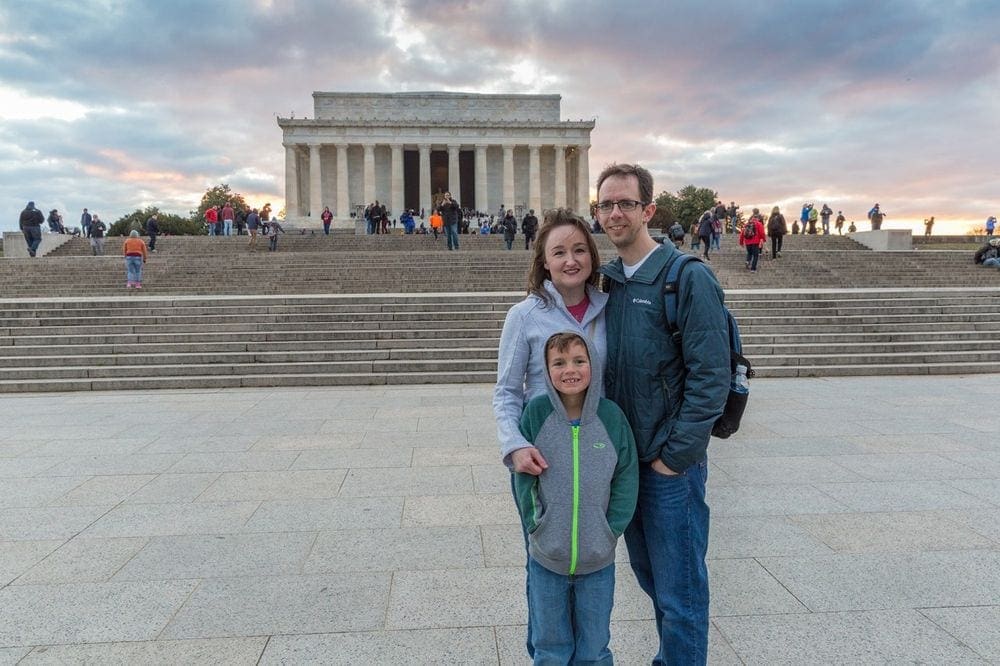 Family of three stands in front of the Lincoln Memorial.