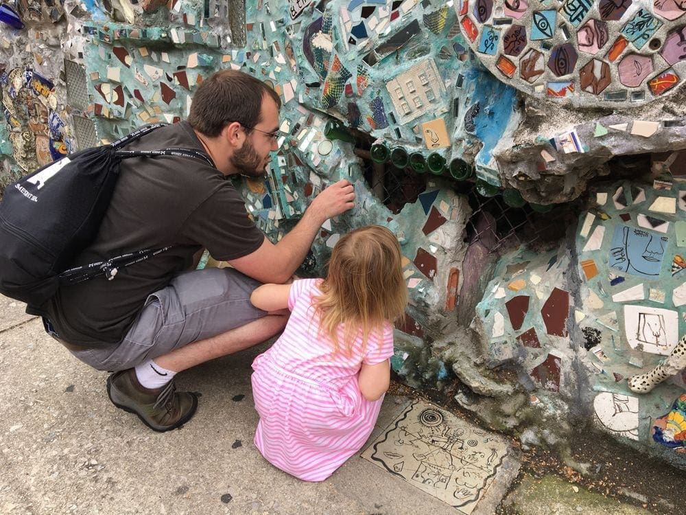Father and child look at mosaic tiles in the Magic Gardens of Philadelphia