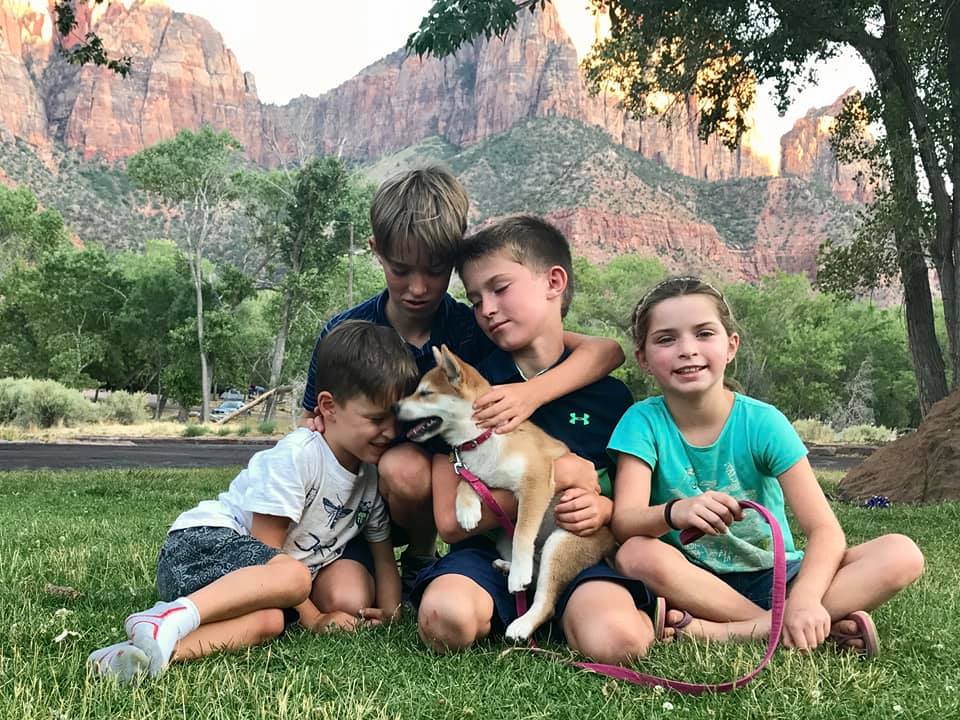 Four kids sit with a puppy in Zion National Park, one of the best places for families in the U.S.