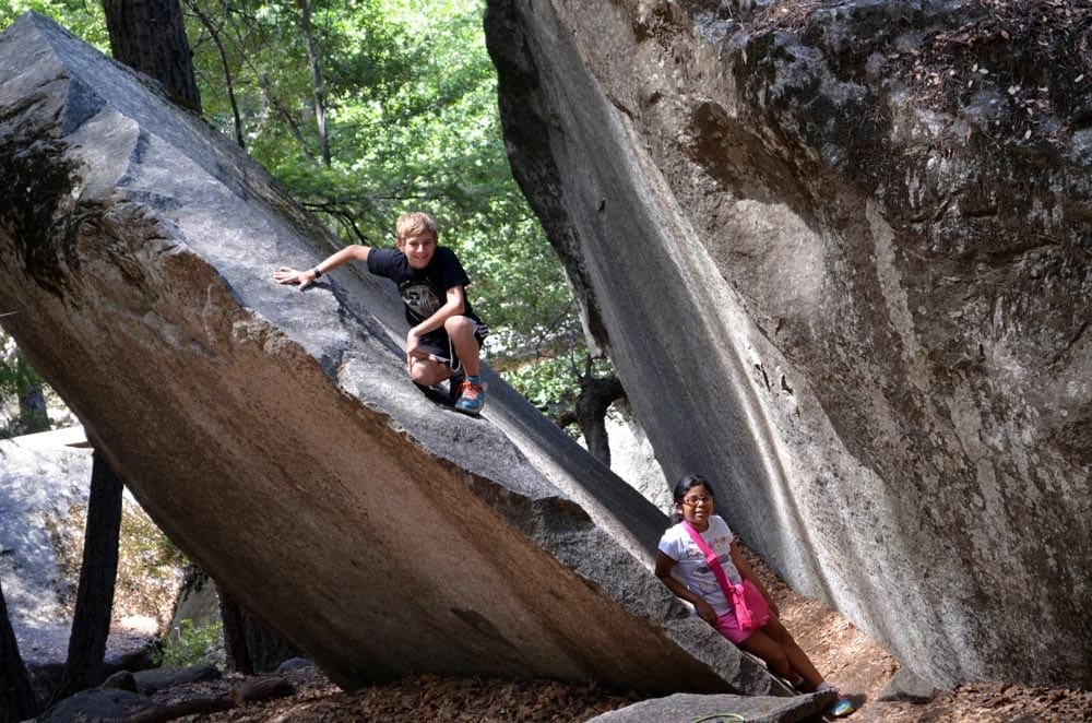 Two kids play in large rocks in Yosemite National Park, one of the best places for families in the U.S.
