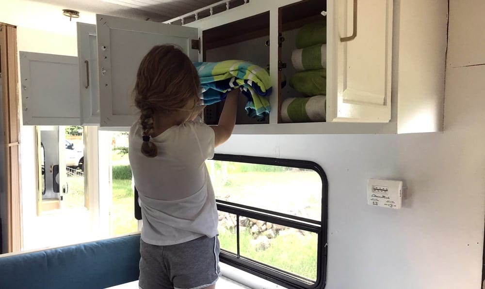 Girl unpacking towels in the trailer. Paking is a key thing to learn for Family RVing For Beginners.
