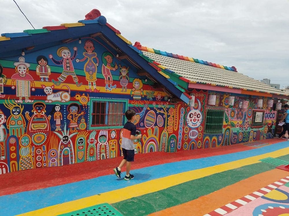 Young boy runs along one of the painted houses in the Rainbow Village of Taiwan.
