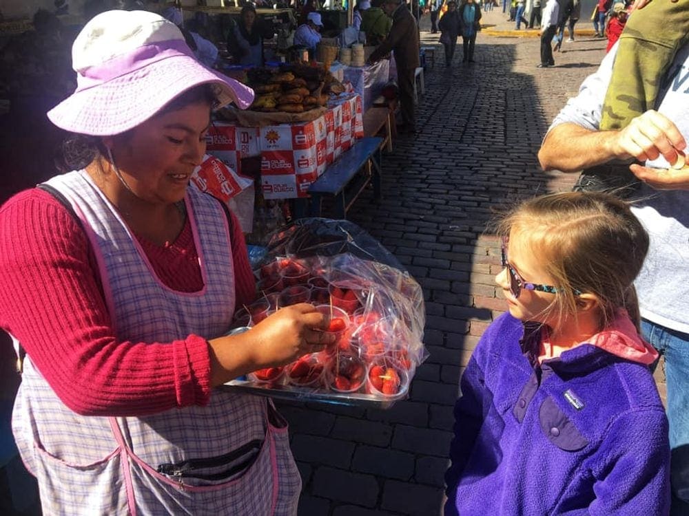 Peruvian woman and young girl talk about fruit at a market in the Sacred Valley of Peru.