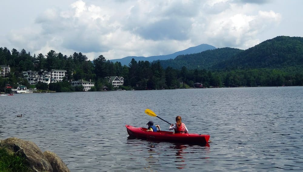 Mom and a son on a kayak in Lake Placid, one of the best lakes in New York State for families.