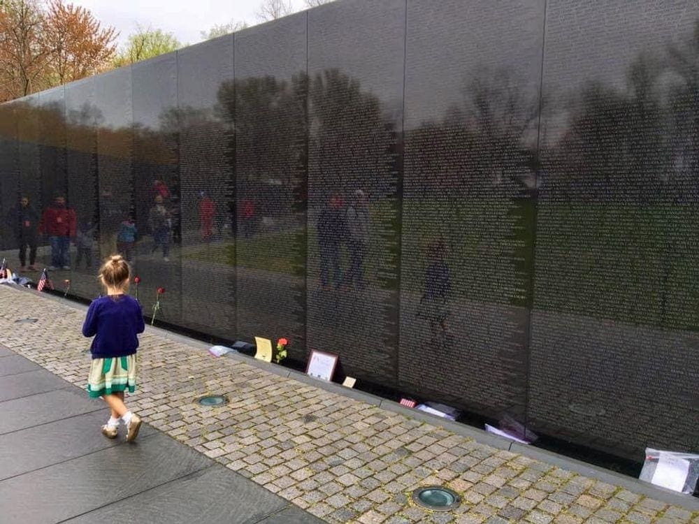 A small girl walks along the Vietnam War Memorial Wall. One of the 9 Things to Do Washington DC with Kids.