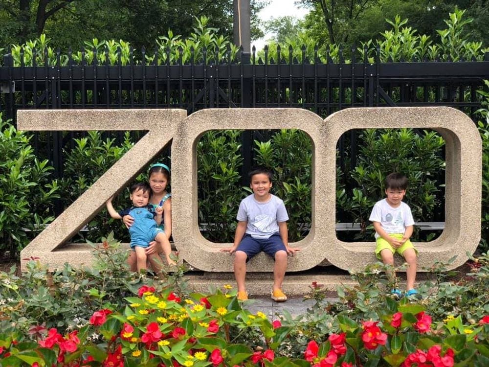 Four kids sit among a sign reading "ZOO" at the Smithsonian Zoo.